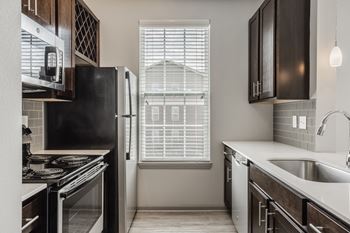 A kitchen with black appliances and wooden cabinets.
